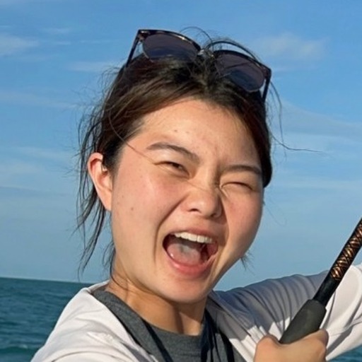 Jade Zhao fishing on a boat, laughing, white sun hoodie, sunglasses on her head.